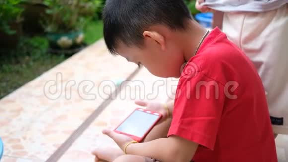 亚洲男孩专心看智能手机视频的预览图