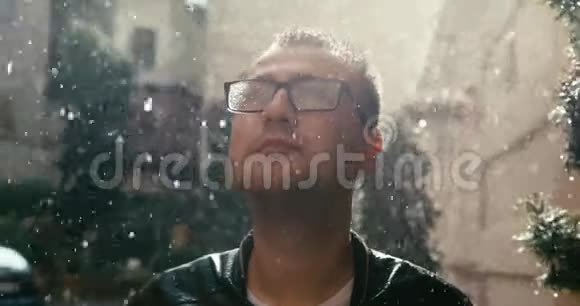 戴眼镜的人正在美丽的阳光花园里抬起脸享受雨天4K录像视频的预览图