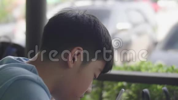 可爱的亚洲男孩使用平板电脑年轻的十几岁男孩在数字平板电脑上做作业默默面对视频的预览图