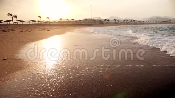日落时海浪在金色沙滩上翻滚的极端慢动作视频视频的预览图