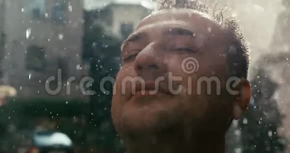 这位轻松的男子在雨中仰望的特写肖像4K录像视频的预览图