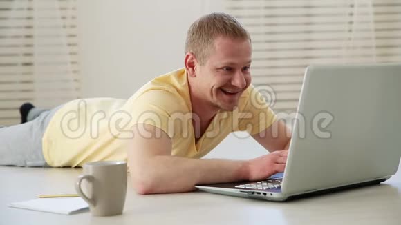 快乐的男人在地板上用笔记本电脑聊天视频的预览图