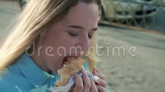 特写镜头拍摄一个女孩在街上吃汉堡包视频的预览图