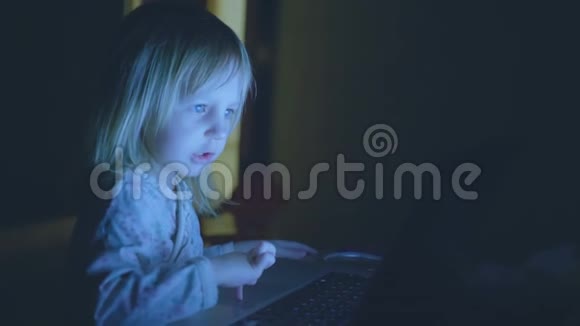小孩子在家里一个黑暗的房间里玩电脑视频的预览图