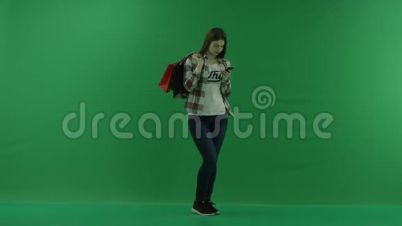 女孩站在半个转弯处看着右边肩上挎着包在绿色的手机旁聊天视频的预览图