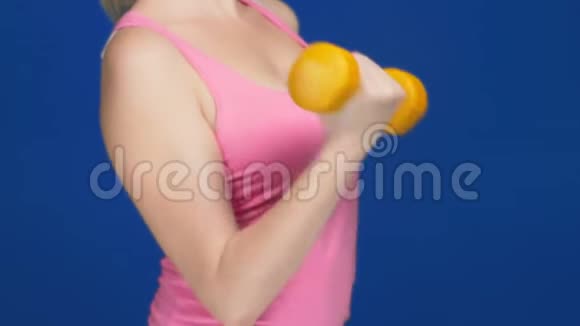 一个穿着一件深领口的粉红色T恤的女人做哑铃凳锻炼肱二头肌复制空间视频的预览图