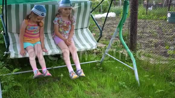 两个女孩姐妹在荡秋千娱乐和户外娱乐活动夏日视频的预览图