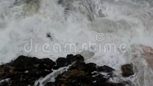 空中缓慢的平底锅粗糙的白色波浪撞击海滩上的岩石视频的预览图