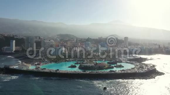 鸟瞰酒店游泳池和海滩被海浪冲刷视频的预览图