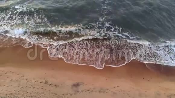鸟瞰日落时热带海滩的一段视频显示傍晚的空中拍摄的绿色泡沫海浪拍打的画面视频的预览图