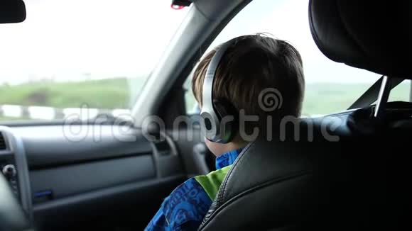 家庭旅行一家人在公路上开车少年坐在车里通过耳机听音乐视频的预览图