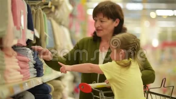 祖母和孙女正在购物中心购买物品孙女坐在购物手推车里视频的预览图