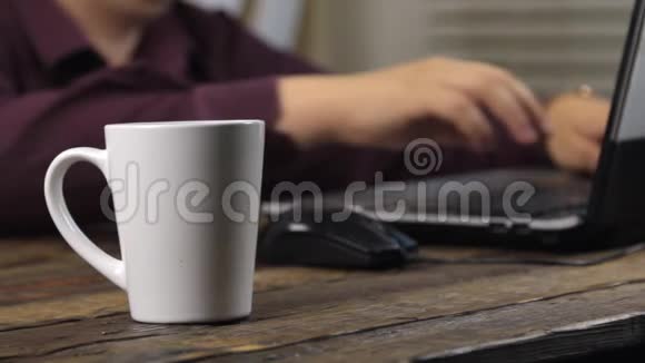 特写杯子里的饮料用电脑鼠标和笔记本电脑键盘工作视频的预览图