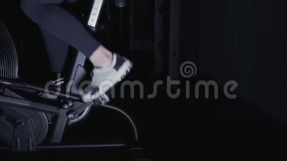 在健身房的自行车机器上穿着运动鞋的女人的腿侧视图平底锅视频的预览图