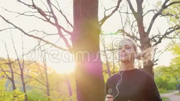 慢镜头健康生活一个女人在春天的森林里慢跑听音乐视频的预览图