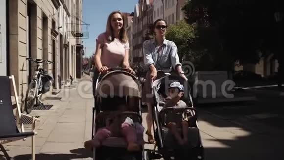 年轻快乐的母亲带着婴儿车的女人走在街上说话散步视频的预览图