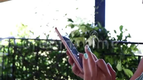 年轻女性在度假时坐在阳台上用智能手机输入短信视频的预览图