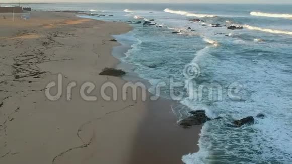 日出时海浪拍打在沙滩上的空中慢动作视频的预览图