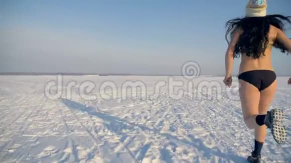 一个穿泳衣的女人在雪地上慢跑作为训练的常规视频的预览图