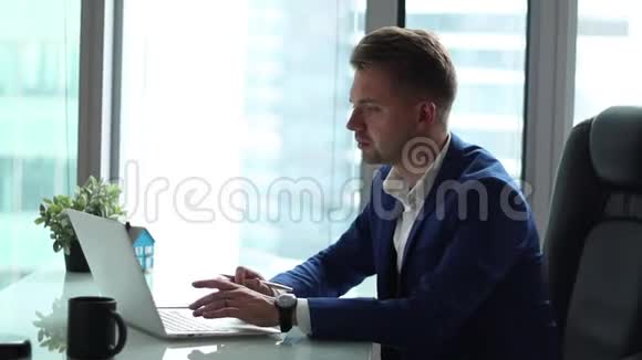 年轻英俊的商人在他办公室的电脑上工作视频的预览图