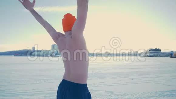 健康的裸胸男子站在雪地上伸展视频的预览图