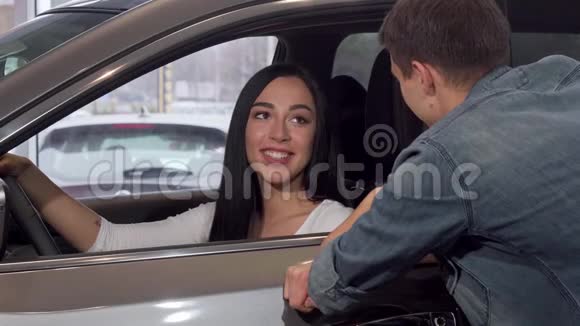 一位漂亮的女士带着车钥匙坐在经销商的新车里视频的预览图