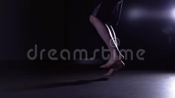 男人的腿在黑暗的健身房跳绳侧视视频的预览图