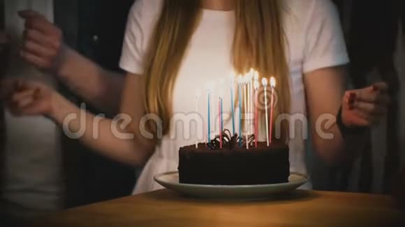 人们围着生日蛋糕和蜡烛跳舞朋友们一起庆祝穿白衬衫的女孩拿着馅饼派对4K视频的预览图