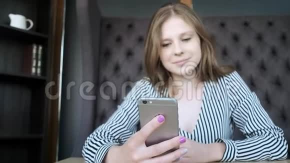 年轻漂亮的女孩在时尚咖啡馆使用智能手机使用应用程序在窗户对面视频的预览图