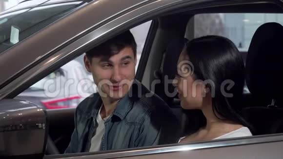 年轻的幸福夫妇选择新汽车在经销商沙龙视频的预览图