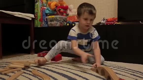 三岁的男孩在客厅里玩木铁路家庭晚餐视频的预览图