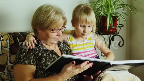 家庭的历史祖母带着孙女叶通过家庭相册视频的预览图