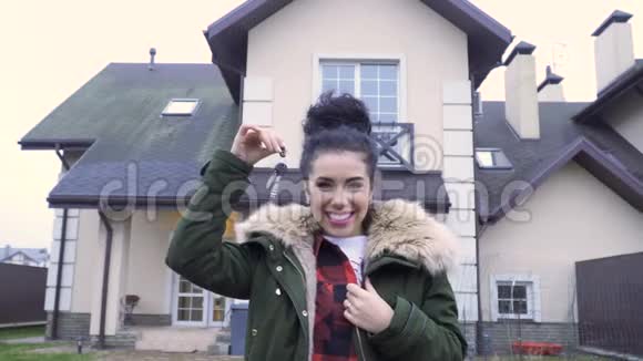 幸福美丽的女人在她的新房子前拿着钥匙视频的预览图
