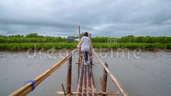 一个女孩在雨天走在竹桥上视频的预览图