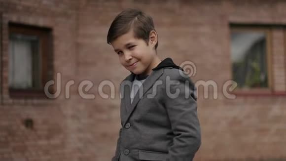 砖墙前留着发型的小男孩对着镜头微笑视频的预览图