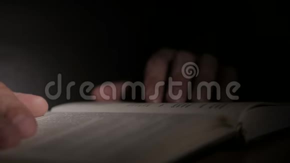 特写一个人手拿着一本打开的纸书用手指翻页视频的预览图