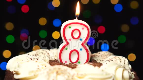在蛋糕上面的8号8岁生日蜡烛燃烧在最后吹灭彩色模糊背景视频的预览图