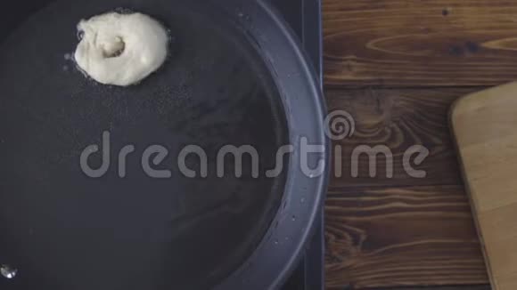 油炸甜甜圈在黑色煎锅里煮油视频的预览图