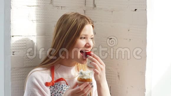 美丽的年轻女子表情忧郁拿着纸杯蛋糕看着窗户视频的预览图