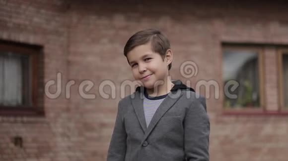 砖墙前留着发型的小男孩对着镜头微笑视频的预览图