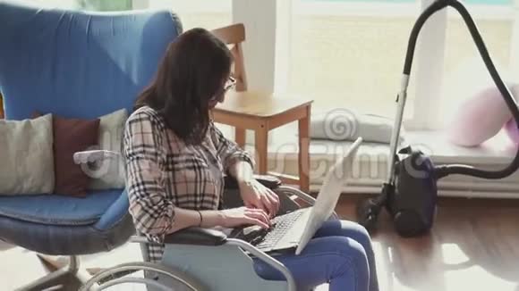 坐轮椅的残疾女孩带着笔记本电脑在他的公寓里视频的预览图