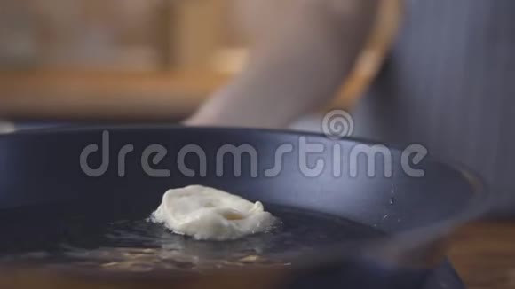 油炸甜甜圈在黑色煎锅里煮油视频的预览图