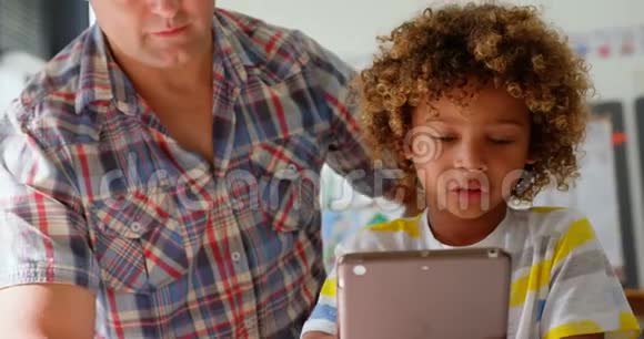 高加索男教师在4k教室的数字平板电脑上教男生的正面视角视频的预览图