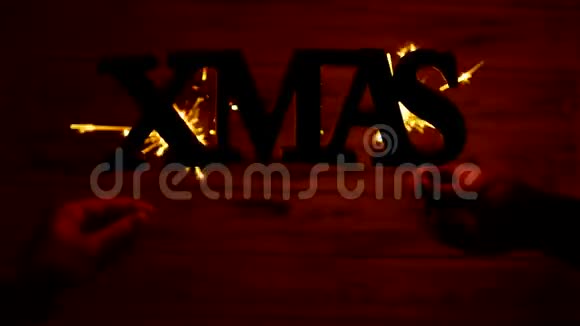 圣诞铭文XMAS自由地悬挂在空中白色的木制背景上火花在背景中燃烧视频的预览图