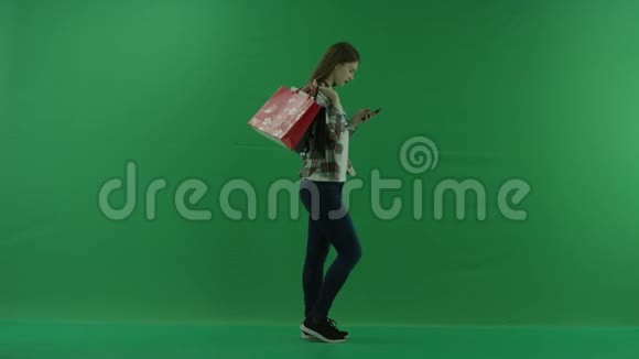 女孩站在她的右边肩膀上放着袋子在绿色屏幕上的手机里写着一些东西视频的预览图