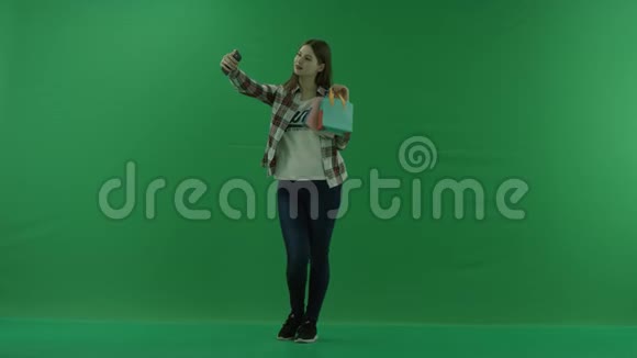 女孩带着迷你包站在半个转弯处向左看在绿色屏幕上自拍视频的预览图
