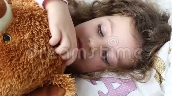 一个小女孩拿着一只玩具熊躺在沙发上特写镜头追踪镜头视频的预览图