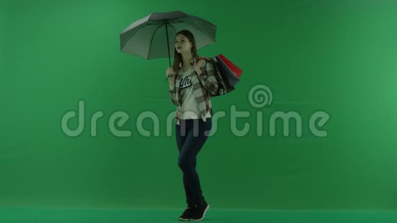 女孩肩上扛着袋子站在伞下半个转弯处看着绿色屏幕的左边视频的预览图