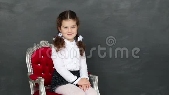 小女孩坐在学校董事会附近的椅子上视频的预览图