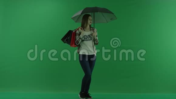 女孩肩上扛着袋子站在伞下半个转弯处看着绿色屏幕的右边视频的预览图